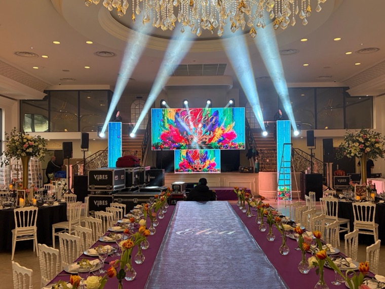 Salle de réception avec mur de LED et colonnes LED aux visuels de plumes colorées, faisceaux de lyres au-dessus des tables