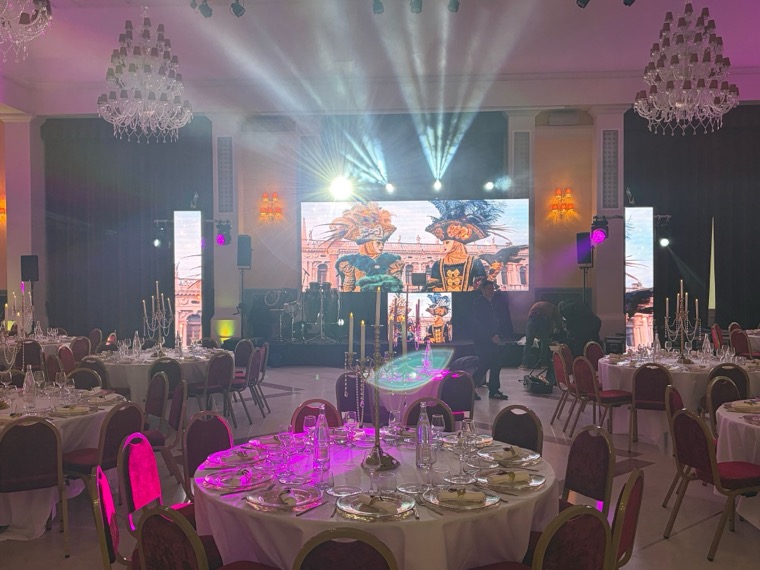 Salle de réception dressée, mur de LED central et colonnes LED diffusant des visuels du carnaval de Venise, faisceaux de lumière