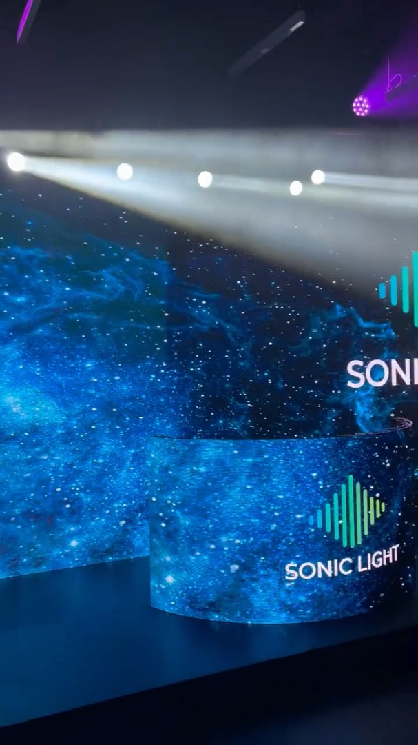 Mur de LED incurvé de 40 m² diffusant un visuel bleu derrière une scène, faisceaux de lumière au-dessus